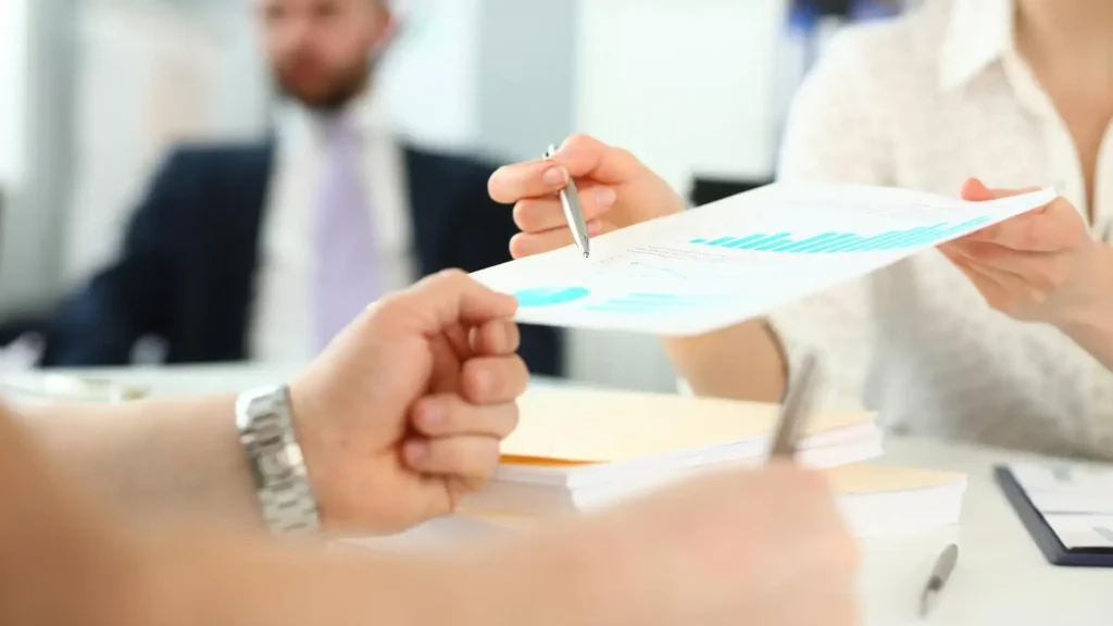 Profesionales intercambiando y analizando un informe con gráficos en una oficina