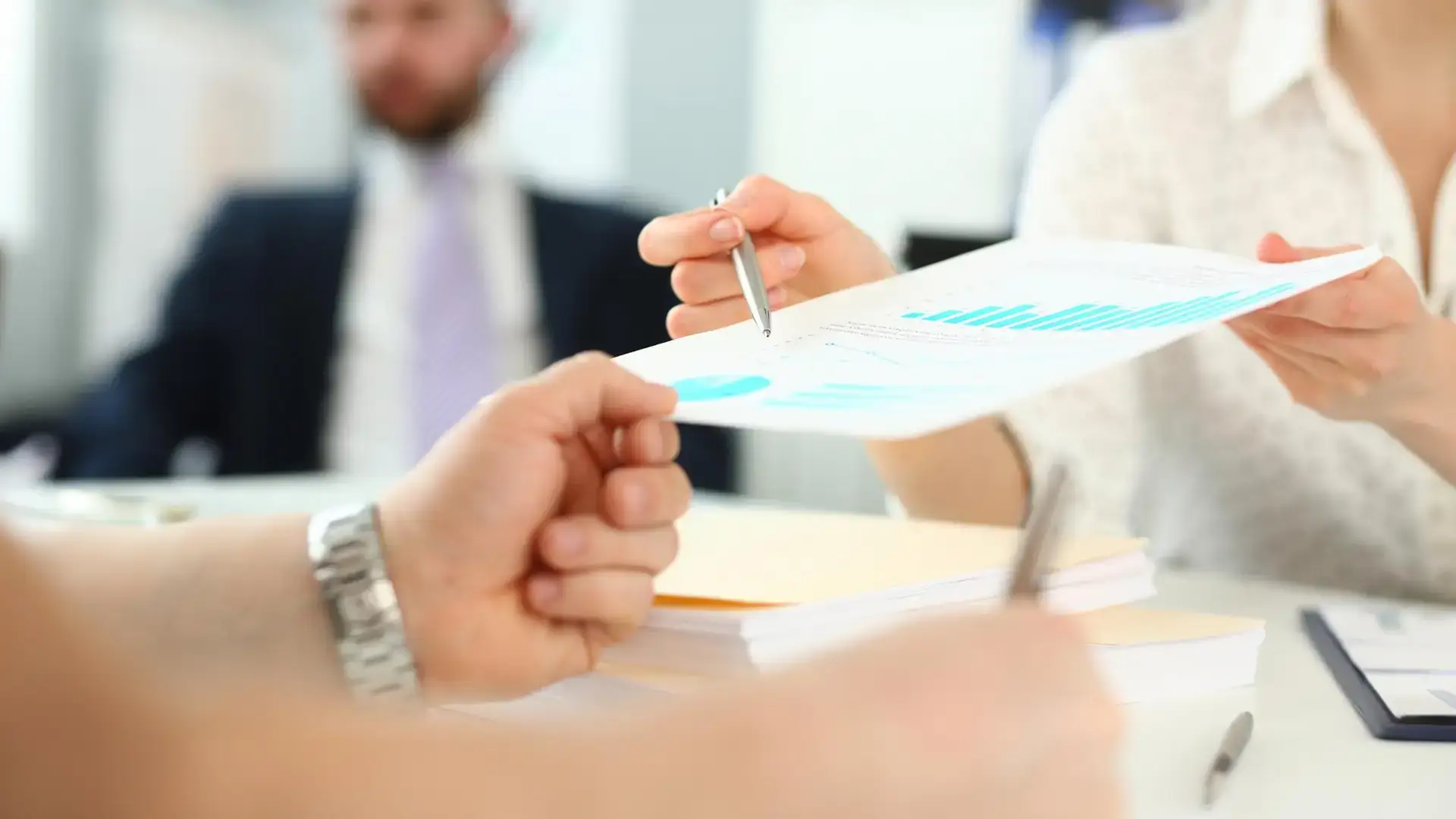 Profesionales intercambiando y analizando un informe con gráficos en una oficina